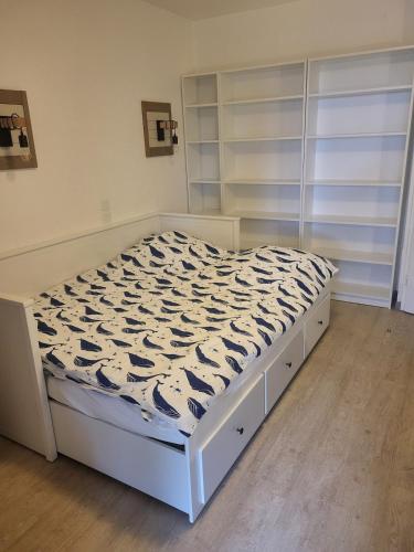 un lit blanc dans une chambre avec des étagères dans l'établissement Perfect holidays, à Saint-Raphaël