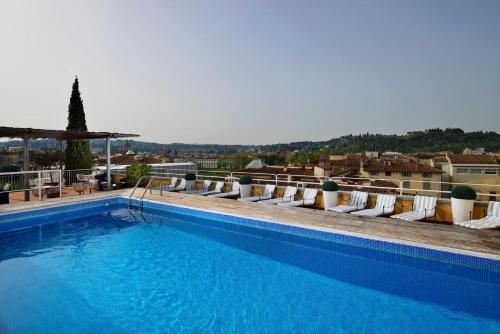 a large swimming pool with white chairs and a view at Hotel Kraft in Florence