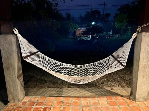 a white hammock hanging on a patio at night at The Say Ba Homestay at Mae Chaem เด๊อะเซ่บะ โฮมสเตย์ แม่แจ่ม in Mae Chaem