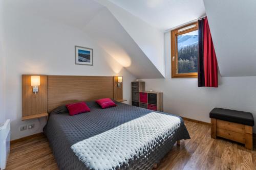 une chambre avec un lit avec deux oreillers rouges dans l'établissement Les Chalets De Bois MÉan - A - Chaleureux duplex pour 6 personnes aux Orres 1800 MAE-4581, aux Orres