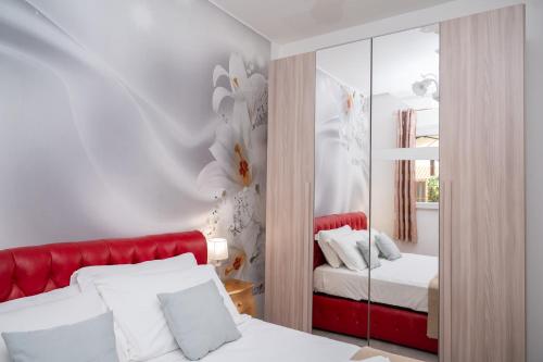 a bedroom with a red bed and a mirror at Dimora Cavallo a 150m da spiaggia sabbiosa in Torre Santa Sabina