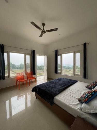 a bedroom with a bed with a ceiling fan and windows at Sky Club Bir Hospitality in Bīr