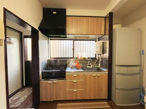 a kitchen with wooden cabinets and a white refrigerator at 花の郷田端b02 in Tokyo