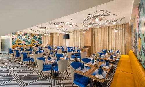 a dining room with tables and blue chairs at Effotel by Sayaji Navi Mumbai in Navi Mumbai