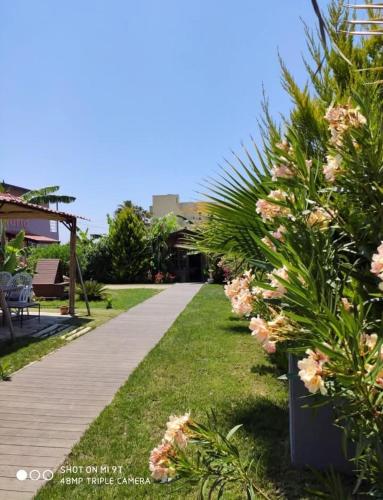 ein Garten mit rosa Blumen und ein Gehweg in der Unterkunft Nostalgia World Boutique Hotel in Kızılot