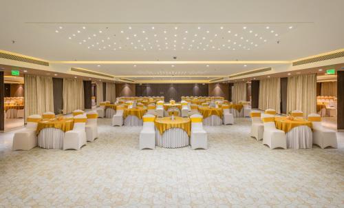 a banquet hall with yellow tables and white chairs at Effotel by Sayaji Navi Mumbai in Navi Mumbai