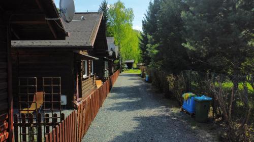 a path next to a fence next to a house at Stanica pod Zadzierną Domki całoroczne in Lubawka