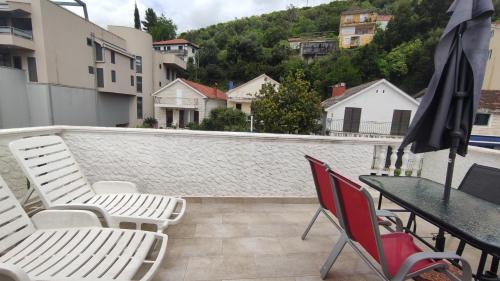 a balcony with chairs and a table and an umbrella at Woodpecker Backpacker Hostel in Herceg-Novi