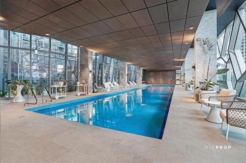 a swimming pool in a building with tables and chairs at The Escape in Southern Cross Station in Melbourne
