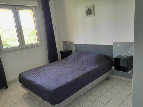 ein Schlafzimmer mit einem Bett mit blauer Bettdecke und einem Fenster in der Unterkunft Home cavalaire in Cavalaire-sur-Mer