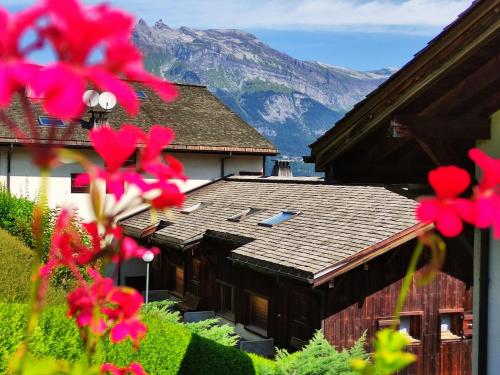 une maison avec une montagne en arrière-plan et des fleurs roses dans l'établissement Duplex Saint Gervais, à Saint-Gervais-les-Bains
