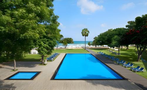an overhead view of a swimming pool with lounge chairs and the beach at Trinco Blu by Cinnamon in Trincomalee