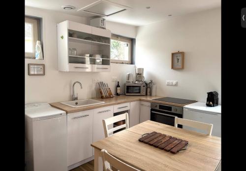 une cuisine avec des armoires blanches et une table en bois dans l'établissement Cottage, L étrille, WIFI gratuit, proche de la mer, jardin, terrasse, à Jullouville