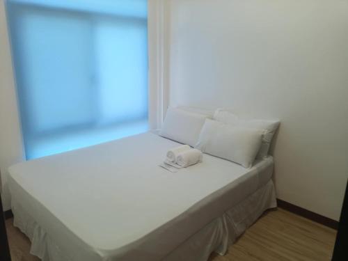 a white bed with white pillows and a window at BMR Apartment-Unit 2 in Dipolog