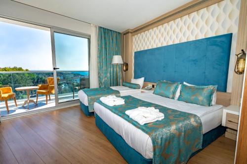 a hotel room with two beds and a large window at The Marilis Hill Resort Hotel & Spa Ultra All Inclusive in Okurcalar