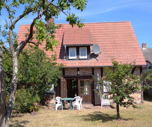 a house with a table and chairs in front of it at Süßes Haus am Haff in Grambin