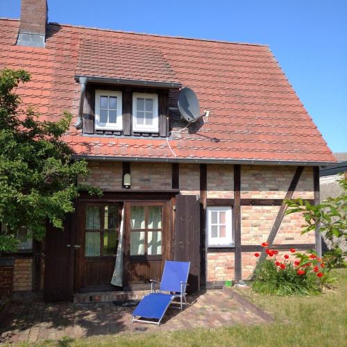 a house with a blue chair in front of it at Süßes Haus am Haff in Grambin