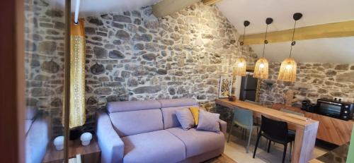 un salon avec un canapé et un mur en pierre dans l'établissement Un nid d'amour, à La Celle-sous-Gouzon