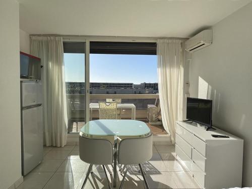 une cuisine avec une table et des chaises devant une fenêtre dans l'établissement Studio Arena Héliopolis AB 315 - 2 personnes, au Cap d'Agde