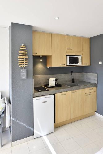une cuisine avec des armoires en bois et un réfrigérateur blanc dans l'établissement Studio Glossy Héliopolis AB 325 - 2 personnes, au Cap d'Agde