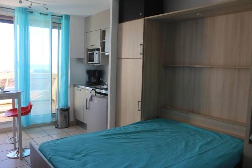 une chambre avec un lit avec une couverture bleue dans l'établissement Studio Makena vue mer Héliopolis AB 330 - 2 personnes, au Cap d'Agde