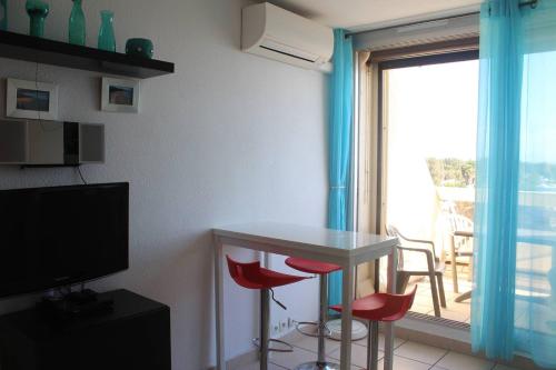 un salon avec une table et des chaises et une fenêtre dans l'établissement Studio Makena vue mer Héliopolis AB 330 - 2 personnes, au Cap d'Agde