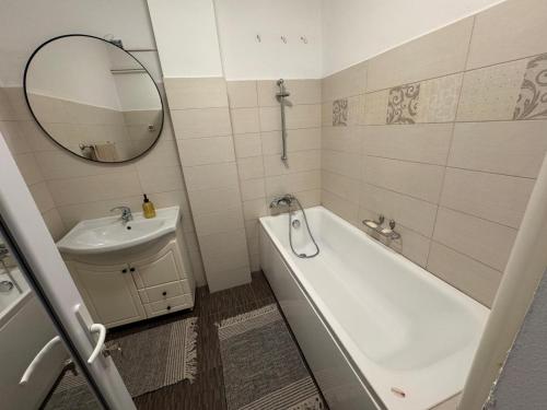 un bagno con un lavandino, una vasca e uno specchio di Clock House a Bucarest