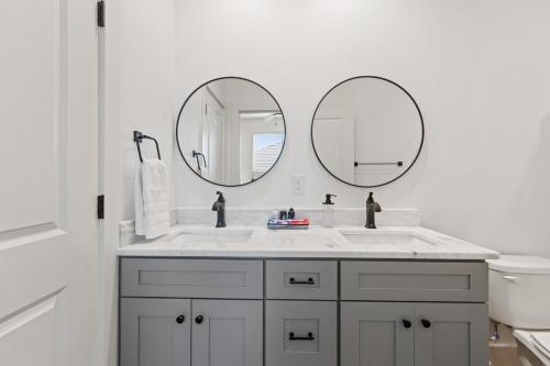 ein Badezimmer mit zwei Spiegeln über einem weißen Waschbecken in der Unterkunft NEW Thibodeaux House Cajun Luxury 65 TV Fast WiFi in Lafayette