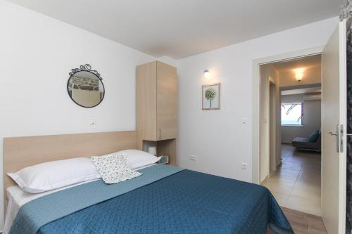 a bedroom with a bed with a blue blanket at Apartments Nikolina in Podgora
