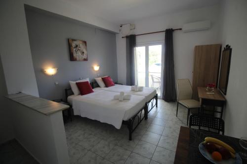 a bedroom with two beds and a table and a window at Tony's Apartments in Agios Georgios