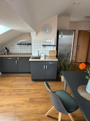 a kitchen with black cabinets and a table and a chair at Ferienwohnungen Steinbacher in Vogtareuth
