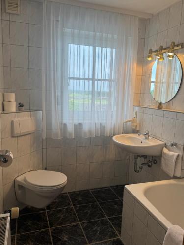 a bathroom with a toilet and a sink and a tub at Ferienwohnungen Steinbacher in Vogtareuth