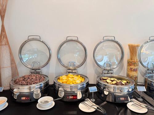 a buffet with four pans of food on a table at The AZURE Arena Cam Ranh Resort in Thôn Hò Ða