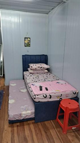 a small bedroom with a bed and a red stool at Warisan Nyonya Cabin Homestay Alor Gajah in Kampong Jelatang