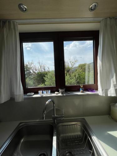 Una cocina con fregadero y dos ventanas. en Villa Esperia, en Caristo