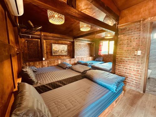 a bedroom with two beds and a brick wall at Mota Homestay in Yên Minh