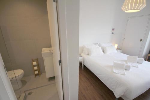 a white bed with white pillows and a bathroom at Lisbon Domus 74 by amcf in Lisbon