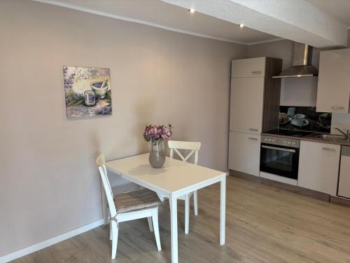 a kitchen with a white table and chairs in a room at Augustenhof Ferien in Nordborg