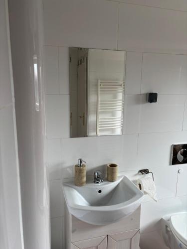 a white bathroom with a sink and a mirror at Augustenhof Ferien in Nordborg