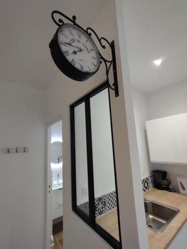 une horloge suspendue sur un mur à côté d'un miroir dans l'établissement Studio Proche Cure Rochefort, à Rochefort