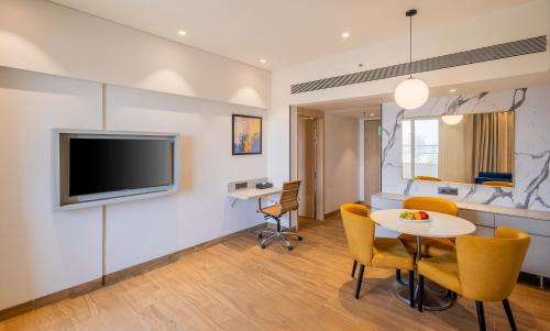 a living room with a table and a tv on a wall at Effotel by Sayaji Navi Mumbai in Navi Mumbai