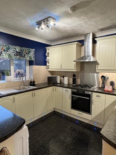 a kitchen with white cabinets and a stove top oven at Cherry Blossom Apartment - 3 bed, parking, garden in Norwich