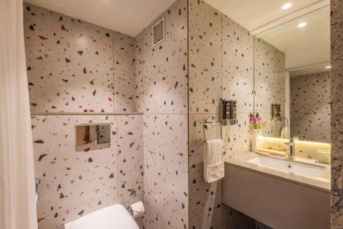a bathroom with a toilet and a sink and a mirror at Effotel by Sayaji Navi Mumbai in Navi Mumbai