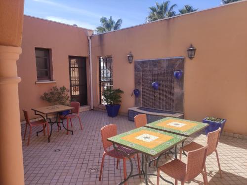 une terrasse avec des tables et des chaises ainsi qu'une cheminée dans l'établissement Chambre Zagora, Riad 8 au village naturiste Couple only, au Cap d'Agde