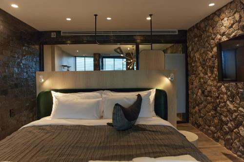 a bedroom with a large bed with a stone wall at Whale Hua Hin - SHA Plus in Hua Hin