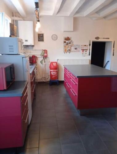 une cuisine avec des armoires rouges et violettes et un comptoir noir dans l'établissement Maison de vacances, à Montoire-sur-le-Loir