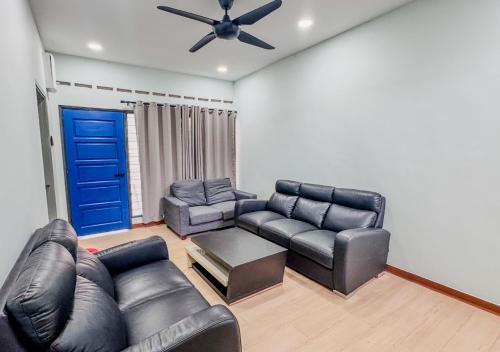 a living room with black leather furniture and a blue door at Casa Azure Shah Alam in Shah Alam
