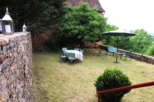 a table and chairs with an umbrella in a yard at Maison du Chapitre in Prudhomat
