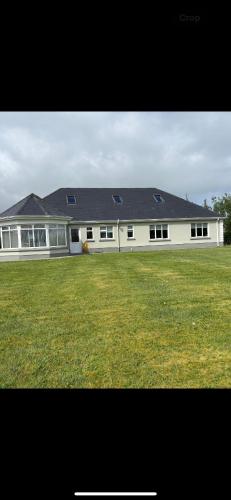 a large white building with windows and a grass field at Albert Lock Bungalow in Carrick on Shannon