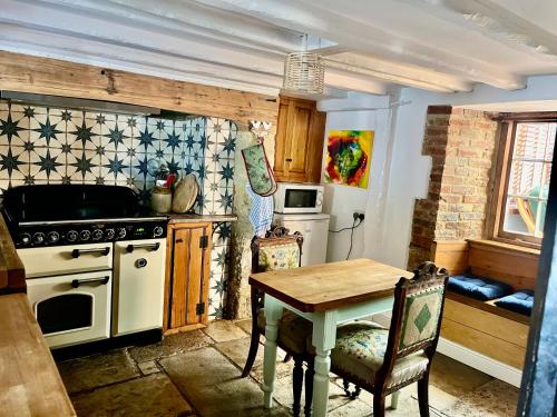 a kitchen with a table and a stove top oven at Christmas Cottage, Isle of Wight in Godshill